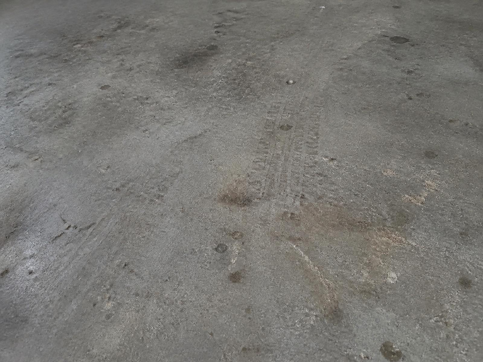 Dull worn garage concrete floor with tyre marks before grinding