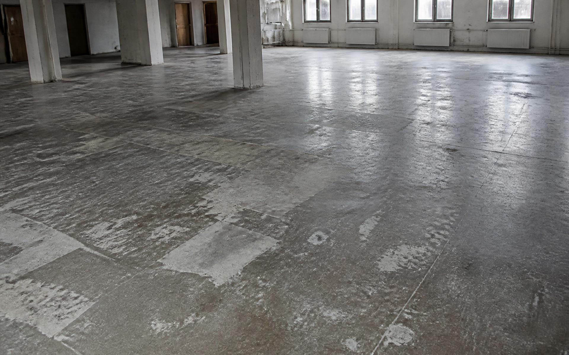 Tired existing concrete floor in an empty interior before grinding