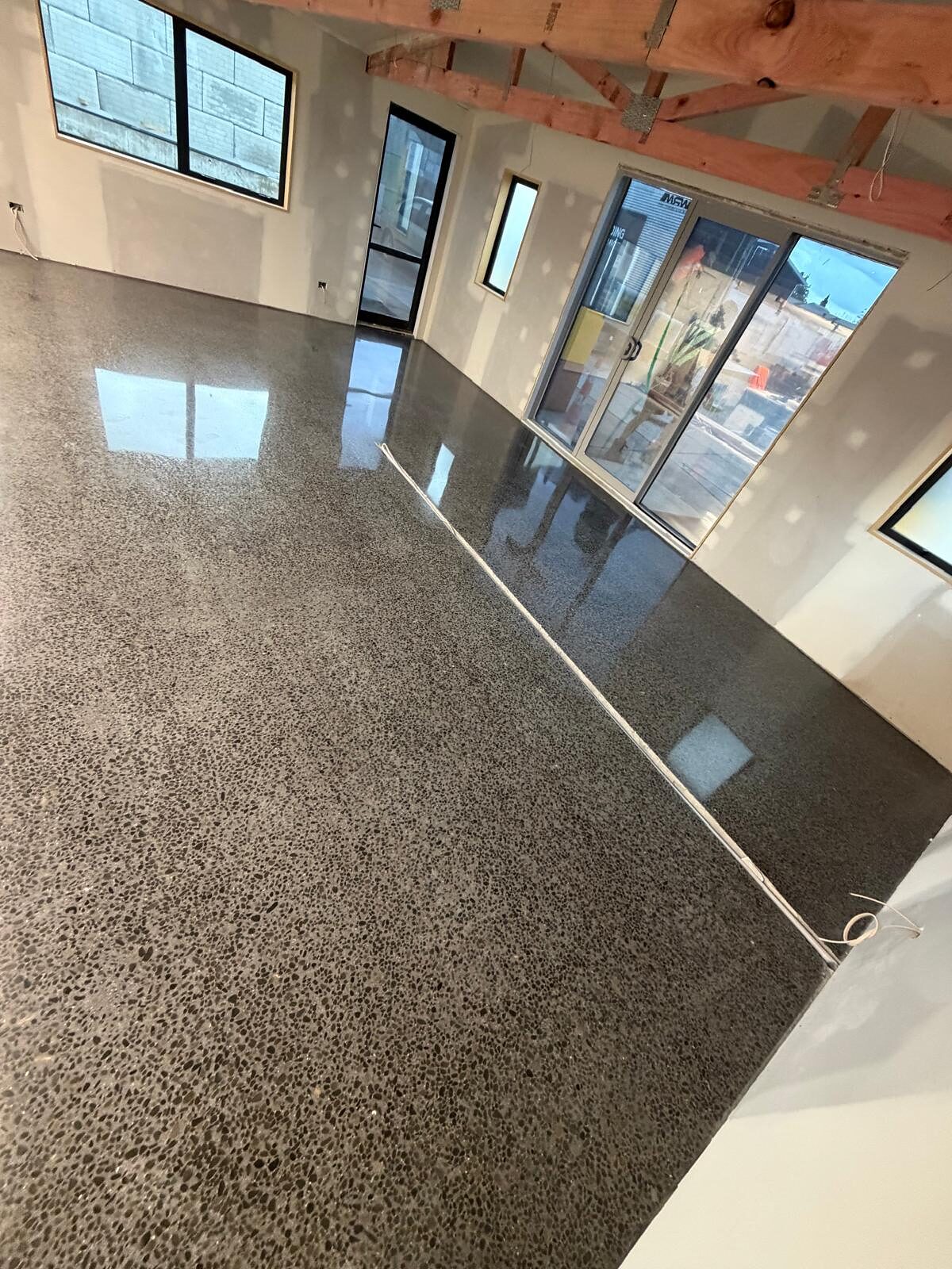 Heavy exposure polished concrete floor with dense dark aggregate cut back to a high gloss