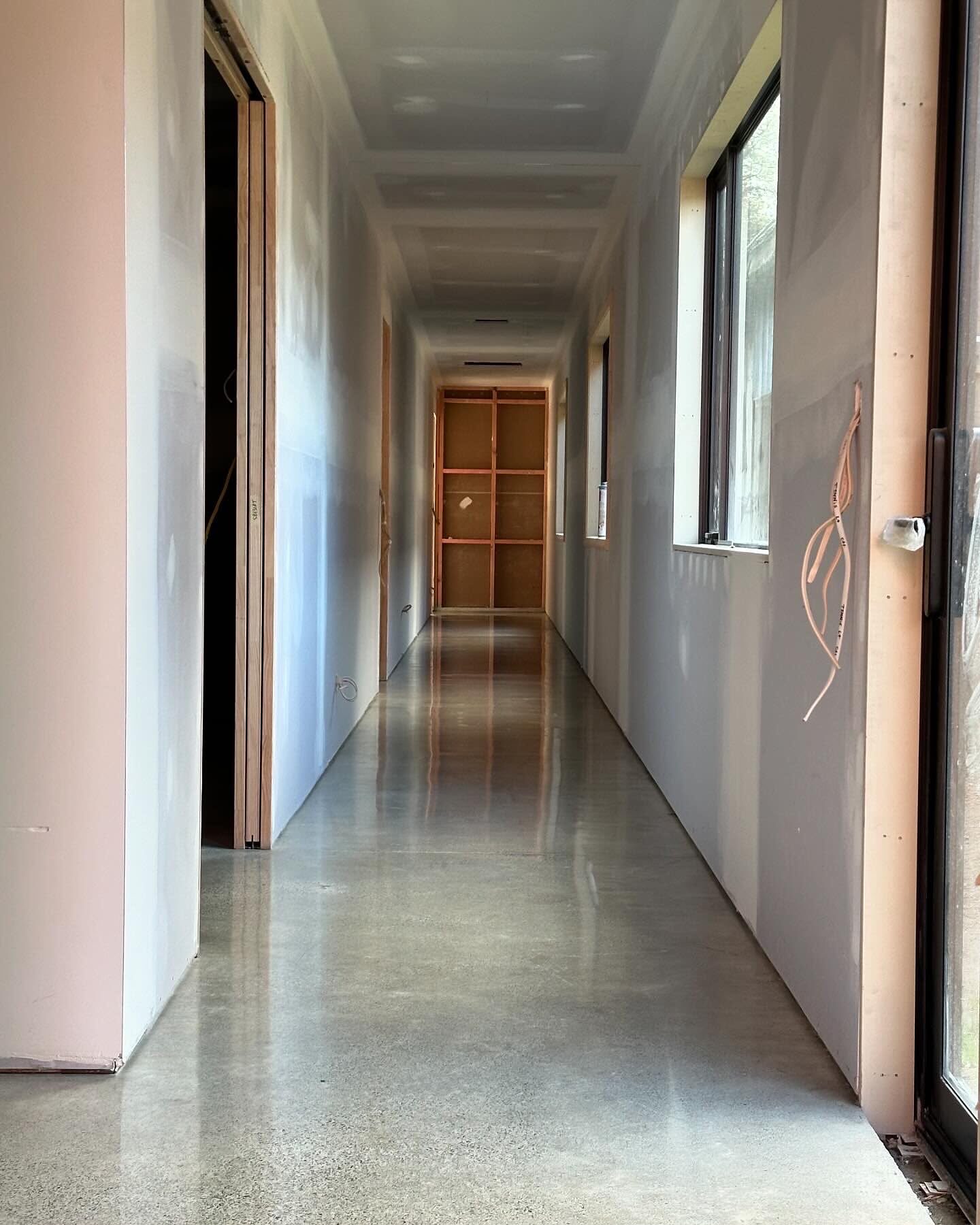 Natural polish concrete hallway floor in a new build, grey slab reflecting daylight from the window wall