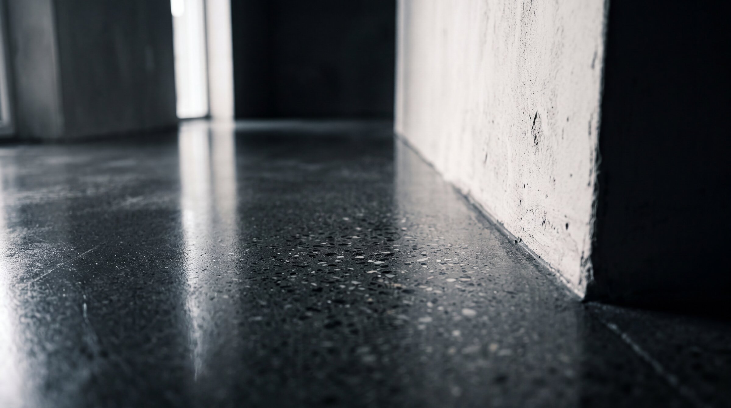 Sealed polished concrete floor with deep reflection meeting a plastered wall